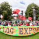 Ralliers hold a large sign reading "Ban Raw Log Exports" in Port Alberni
